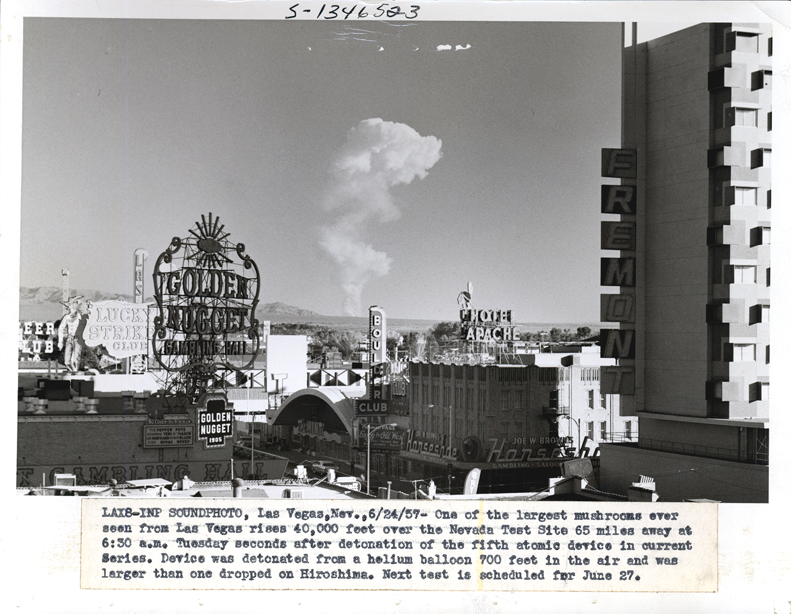 A mushroom cloud is seen in the background behind a Las Vegas skyline. Neon casino signs can are seen in the foreground.