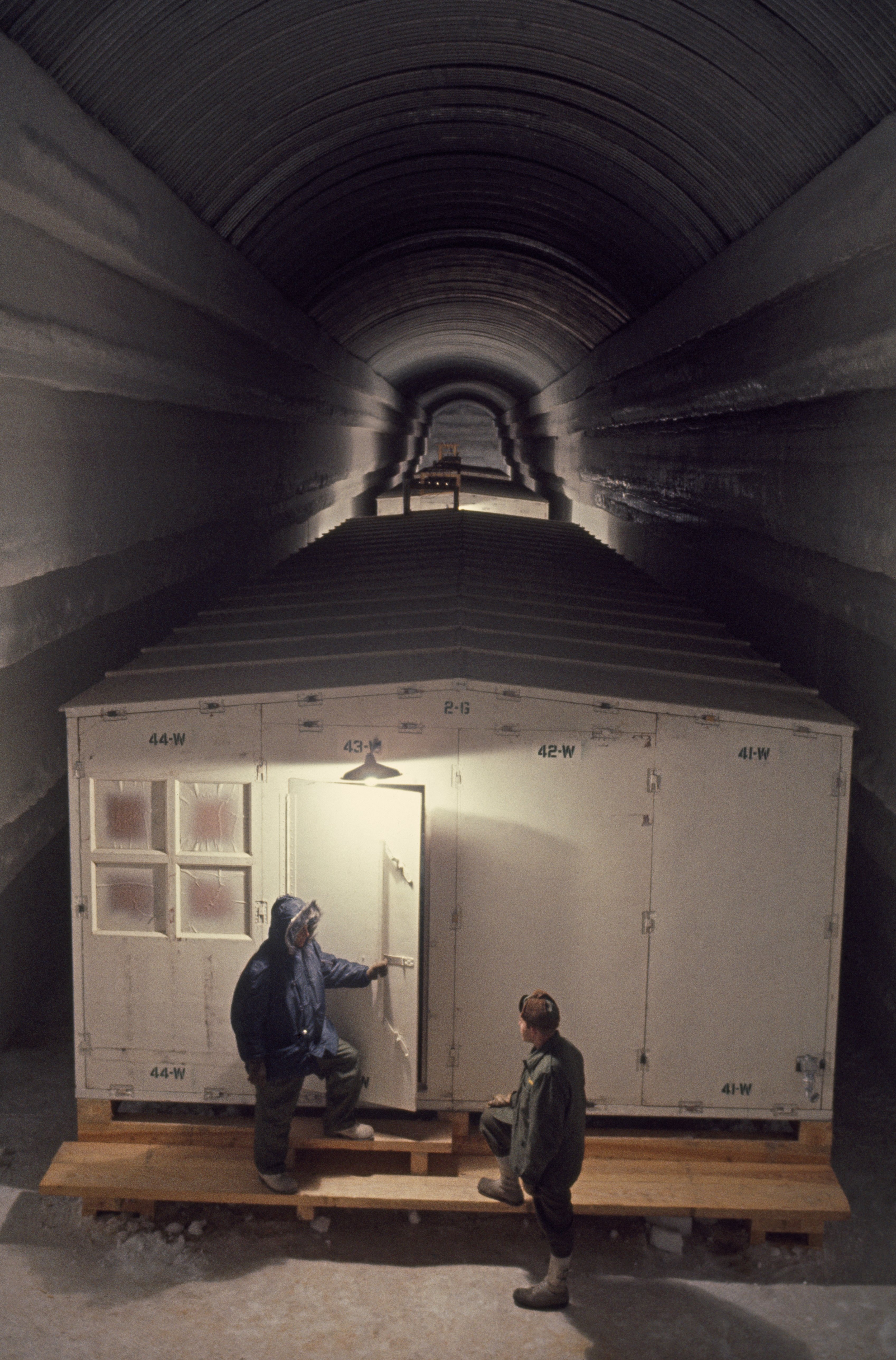 Men stand outside barracks in an Arctic outpost's tunnel, Camp Century, Greenland