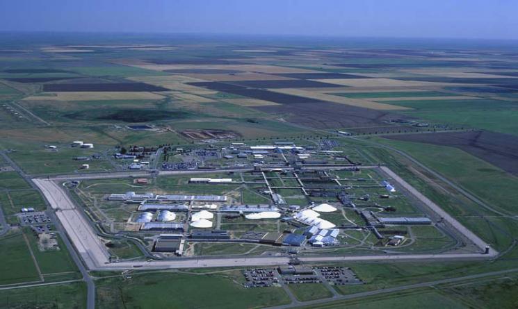 A fenced in low facility sits in a large checkered field.