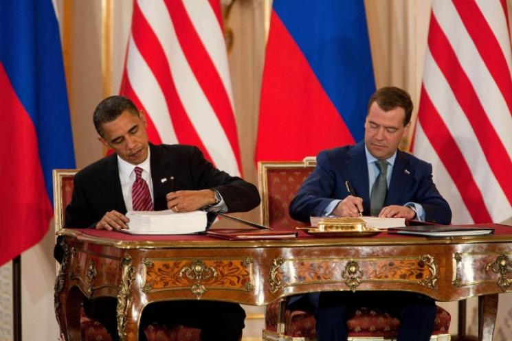 President Barack Obama and Russian president Dmitry Medvedev sit side-by-side, their countries' flags in the background.