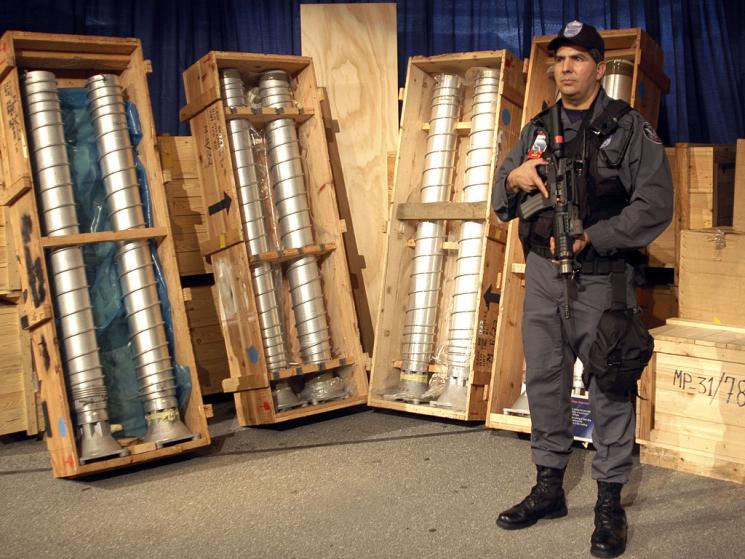 A U.S. soldier stands guard in front of 4 gas centrifuges.