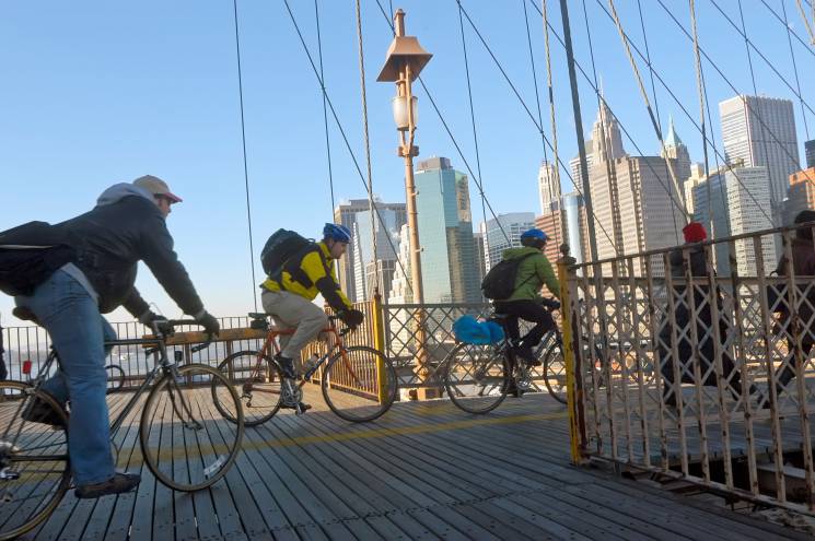 Bike commuters cross a bridge in New York City. Driving less often is one way to reduce your personal impact on the climate.