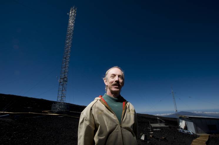 A scientist stands near a meteorological observation tower in Hilo, Hawaii.