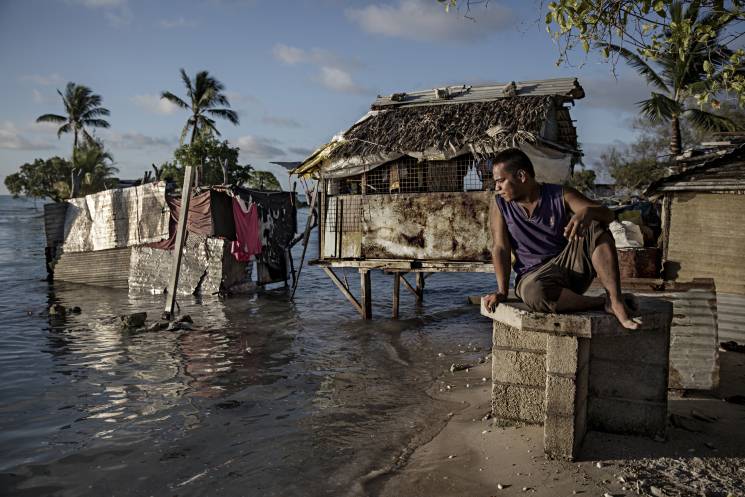 A resident of the village of Eita in Kiribati watches the ocean flood his hometown. The island lies only a few feet above sea level, putting it at risk for flooding and sea swells.
