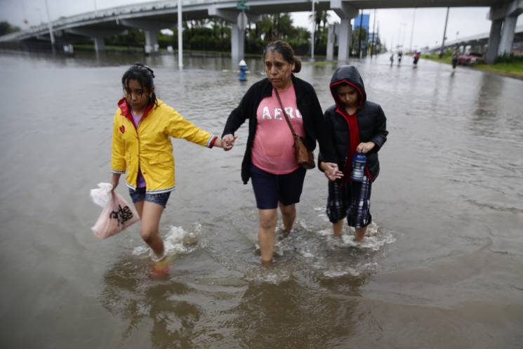 grandmother and two children wade through flood waters