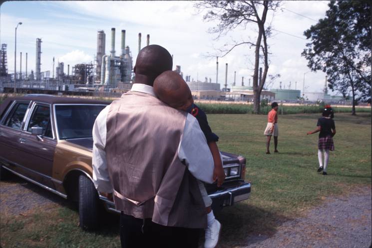A family leaves Sunday church services surrounded by chemical plants in October of 1998 in Lions, Louisiana. The poor, often black towns along the Mississippi River near Baton Rouge are known as "Cancer Alley" for the high cancer clusters and the many chemical and oil production factories.