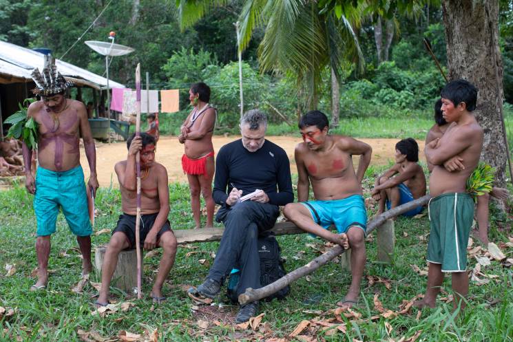 Dom Phillips (C) takes notes as he talks with indigenous people at the Aldeia Maloca Papiú, Roraima State, Brazil, on November 15, 2019. - Phillips went missing while researching a book in the Brazilian Amazon's Javari Valley with respected indigenous expert Bruno Pereira.