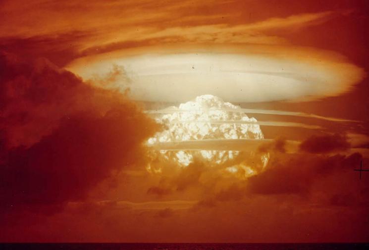 A gigantic mushroom cloud lights the sky a bloody orange.
