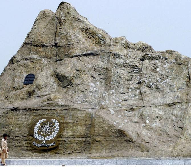 Two Pakistani men walk past the replica of the Chagi mountain, where Pakistan held its first nuclear test in July of 2004.