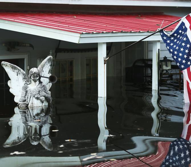 A statue and an American flag are seen outside a home flooded by water coming from the breached dams upstream as the water continues to reach areas in the eastern part of the state on October 9, 2015 in Andrews, South Carolina. The state of South Carolina experienced record rainfall amounts causing severe flooding and officials expect the damage from the flooding waters to be in the billions of dollars. (Photo by Joe Raedle/Getty Images)
