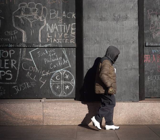 man walks by building with Black Lives Matter messages in chalk on the walls