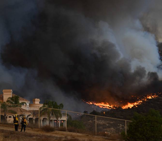 Plumes of smoke rise as wildfire approaches a home during the Fairview Fire near Hemet, California in Riverside County on September 7, 2022. 