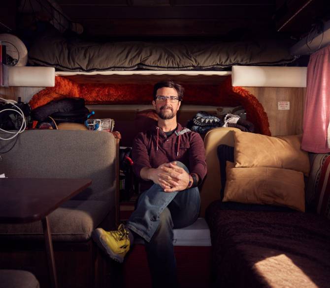 Brian Gifford’s compact 1977 motor home has wall-to-wall orange shag carpeting and rooftop solar panels. Knowing his home is a gas guzzler, he drives only when switching camping locations and has a Geo Tracker in tow for getting around.