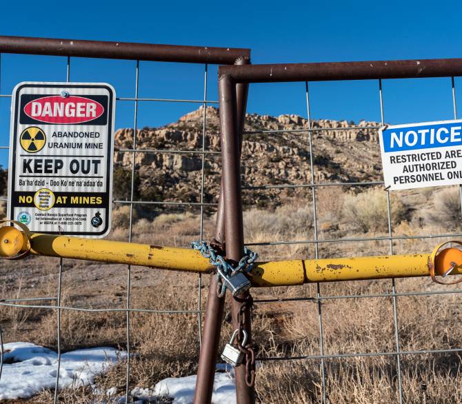 Signs warning of health risks are posted outside the gates of an abandoned uranium mine in the community of Red Water Pond Road, N.M. Credit: The Washington Post via Getty Images