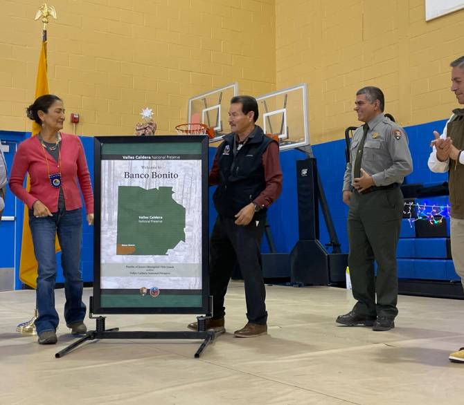 Secretary of the Interior Deb Haaland, second from the left, helped Pueblo of Jemez Gov. Peter Madalena, center, unveil a poster showing Valles Caldera National Preserve in north central New Mexico, during the event on December 22 celebrating the settlement upholding the pueblo’s entitlement to its ancestral land, including Banco Bonito, inside the national preserve. Credit: Noel Lyn Smith/Inside Climate News