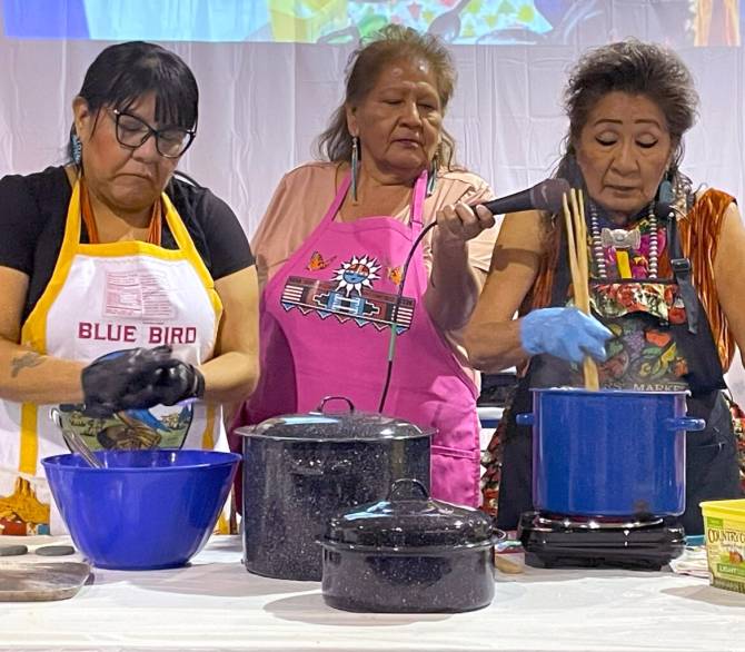 Tennile Lopez (left) shapes blue corn dough while Bertha Etsitty (right) explains the process of blue corn mush on Nov. 25 at the food gathering summit held by Diné College's Land Grant Office. 
