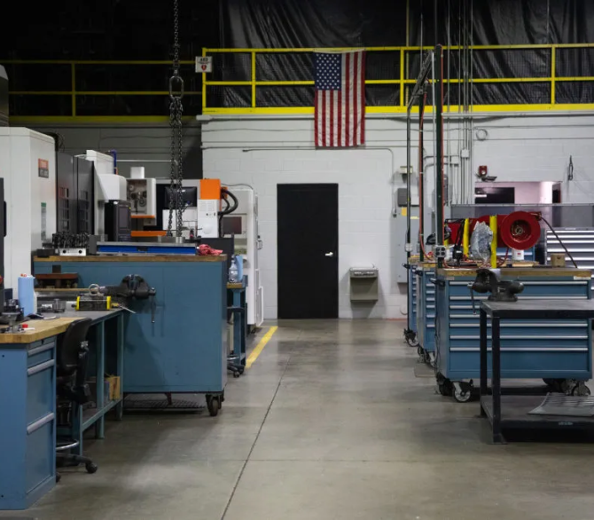 An American flag hangs above empty work stations at the Clips & Clamps Industries manufacturing facility in Plymouth, Michigan, U.S., in April 2020.