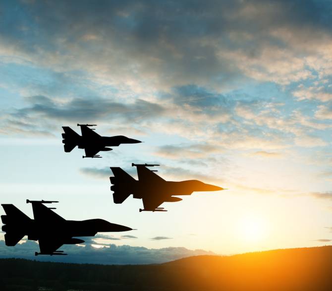 Fighter jet silhouettes on background of sunset.