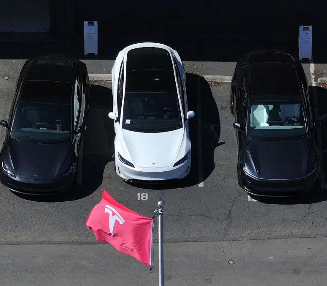 In an aerial view, brand new Tesla cars sit parked in a lot at a Tesla dealership on April 2, 2025 in California. 