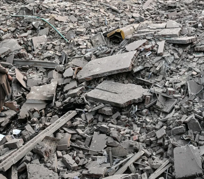 Locals stand on the debris of destroyed structures at the Government Health and Educational complex in Muridke about 30 kilometers from Lahore, on May 7, 2025, after Indian strikes. The death toll from Indian strikes on Pakistan has increased to eight, the country's military spokesman said on May 7, as India fired missiles at Pakistani territory and Islamabad vowed to 