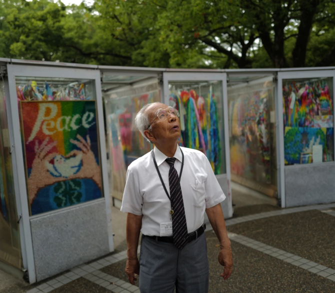 Kunihiko Iida, an atomic bomb survivor and volunteer guide who speaks English to foreign visitors, looks up the sky in front of the Children’s Peace Monument, where people offer paper cranes to honor the victims of the 1945 atomic bomb, on Wednesday, July 9, 2025, in Hiroshima, western Japan. 