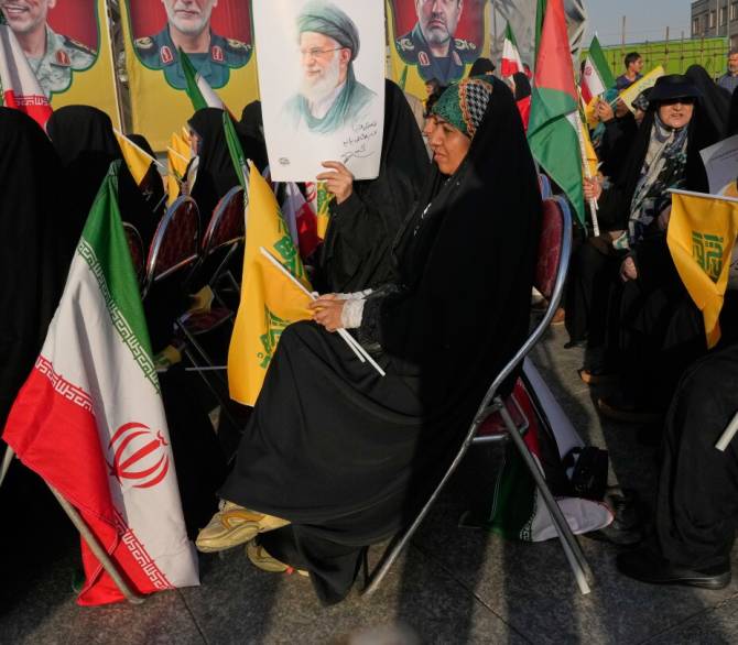 A woman holds a poster of the Iranian Supreme Leader Ayatollah Ali Khamenei as portraits of the late Iranian armed forces commanders, who were killed in Israeli strike in June, are seen at background, during a commemoration marking the first death anniversary of Hezbollah leaders Hassan Nasrallah and Hashem Safieddine, who were killed in Israeli airstrikes in Beirut, in Tehran, Iran, Thursday, Oct. 2, 2025. 