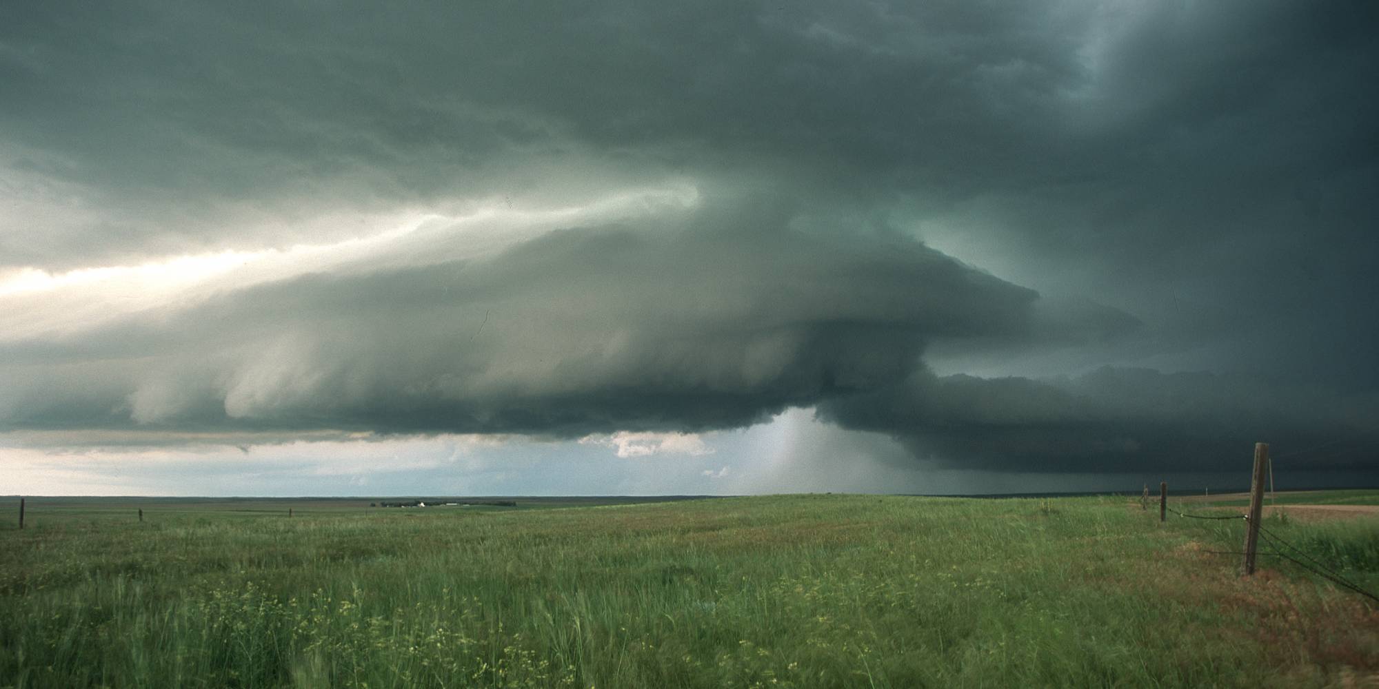 A storm gathers over a field of grass